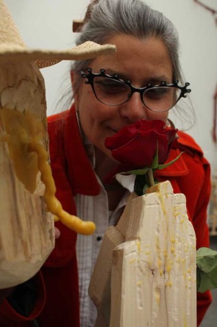 Susan Calza leans over a student's sculpture at her last students' exhibit.