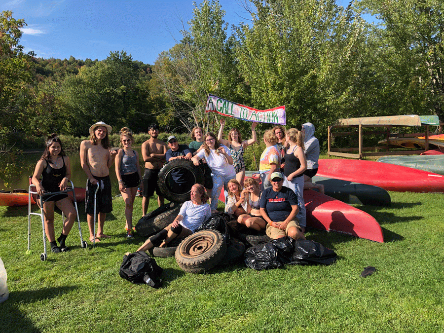 The Call to Action first-year seminar class poses with the 8 tires they found in the Lamoille River.