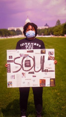 Devyn Thompson standing with her sign to represent her recently published book of poetry.